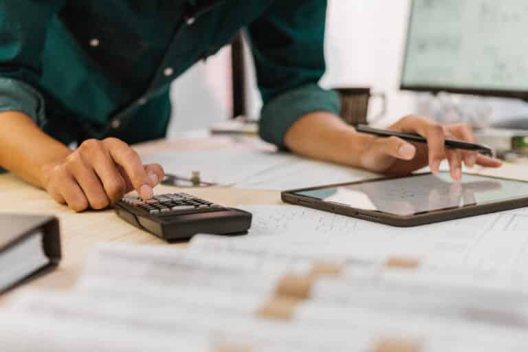 Person using calculator and tablet for estimating plumbing costs