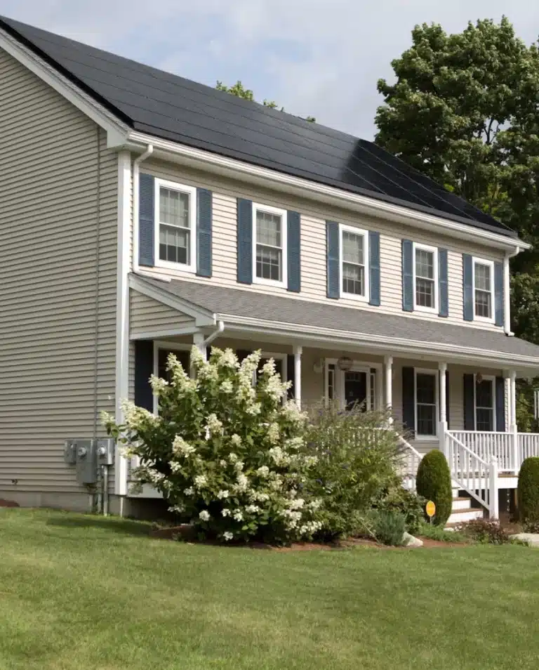 Front view of a two-story house with solar panels on the roof and a well-maintained lawn